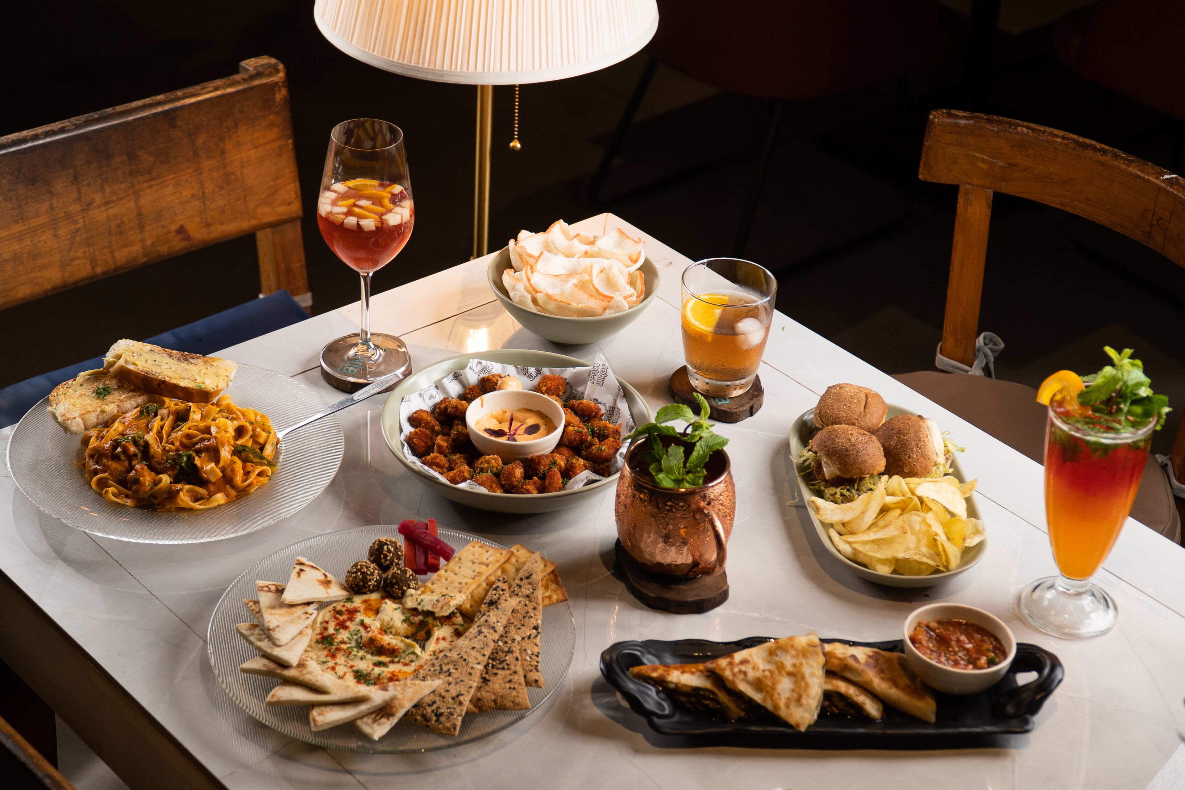 A dining table with various dishes, including pasta, bread, and a drink.