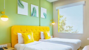 A hotel room with two beds, a window with a view, and artwork on the wall. - Bloom Hotel - Heritage Walk (Amritsar)