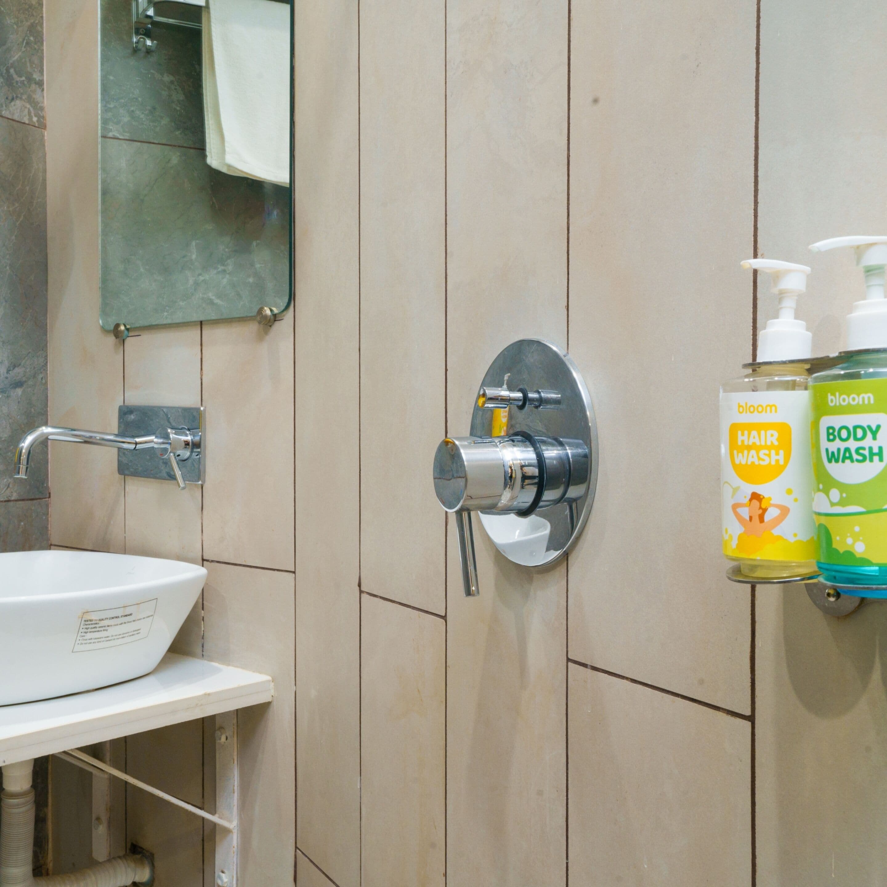 A bathroom with a white sink, a mirror, a towel rack, and two bottles of hair and body wash.