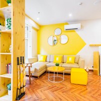 Una sala de estar moderna con una paleta de colores amarillo y blanco, que incluye un sofá, una mesa de centro y una estantería.