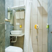 Un baño con lavamanos blanco, inodoro, cortina de ducha y espejo.