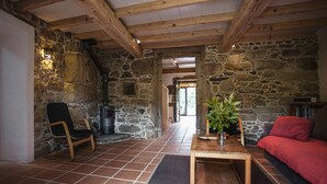 A rustic interior with stone walls, wooden beams, a fireplace, a red sofa, and a wooden table with a plant. - One of two private and intimate casitas. Surrounded by nature. (Moraña)