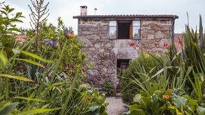 A stone house with a gravel path leading to the entrance, surrounded by lush greenery and flowering plants. - One of two private and intimate casitas. Surrounded by nature. (Moraña)