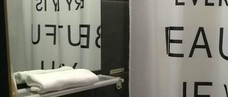 A bathroom with a white sink, a mirror, and a shower curtain with text.