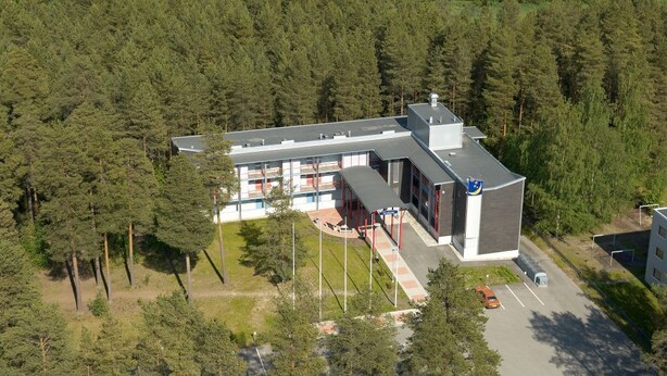 A modern building with a flat roof, surrounded by dense forest. - Hotelli Uusikuu (Mikkeli)