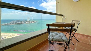 A balcony with a view of a beach, a Ferris wheel, and a cityscape. - Marco Polo - Full Sea & Dubai Eye View | 2 BR | Near JBR Beach (Dubai)