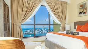 A hotel room with a large window, a bed with orange pillows, and a view of a Ferris wheel. - Marco Polo - Full Sea & Dubai Eye View | 2 BR | Near JBR Beach (Dubai)