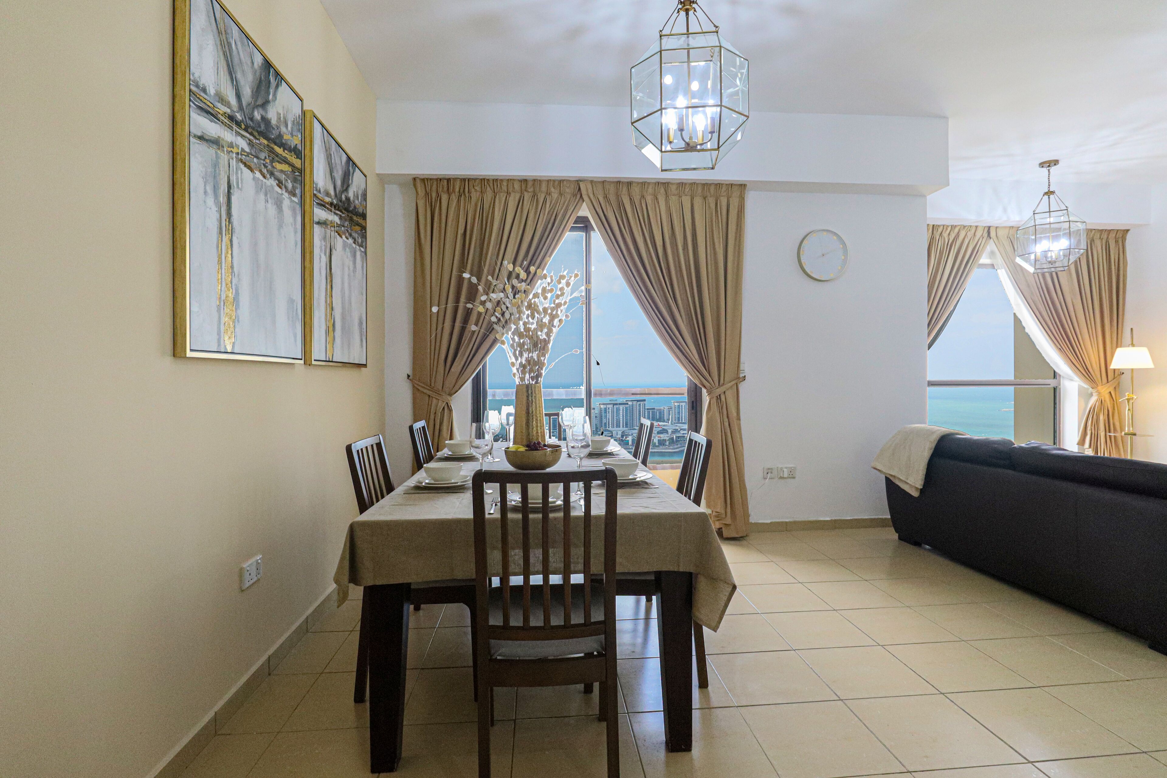 A dining area with a table set for four, a sofa, and a view of the city.
