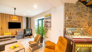 A modern living room with a sofa, armchair, and a Wurlitzer jukebox. - Charming Holiday Home Near Namur With Private Sauna (Jemeppe-sur-Sambre)