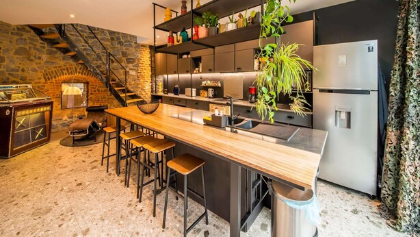 A modern kitchen with a central island, bar stools, a built-in stove, and a refrigerator. - Charming Holiday Home Near Namur With Private Sauna (Jemeppe-sur-Sambre)