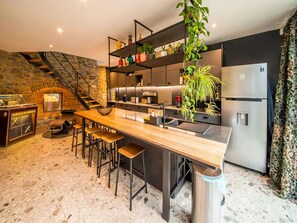 A modern kitchen with a central island, bar stools, a built-in stove, and a refrigerator. - Charming Holiday Home Near Namur With Private Sauna (Jemeppe-sur-Sambre)