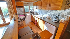 Kompakti keittiö, jossa on puukaapit, mikroaaltouuni, pesuallas ja kahvinkeitin.