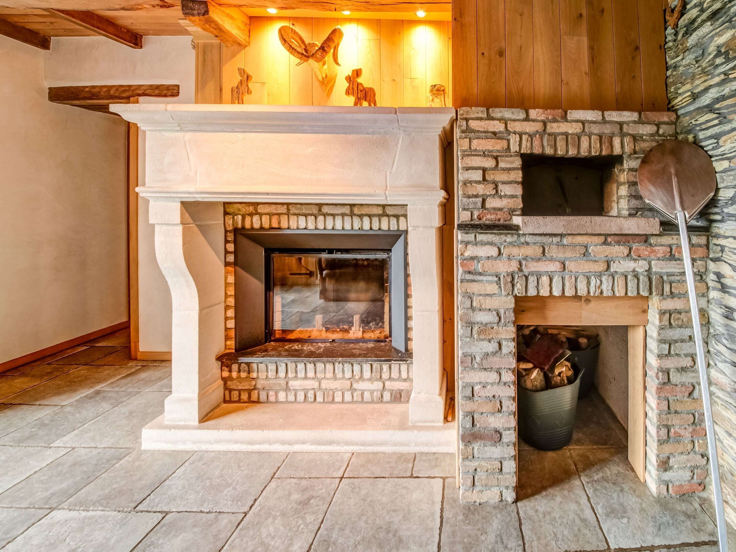 Una chimenea con un revestimiento de piedra y un fuste de madera encima.