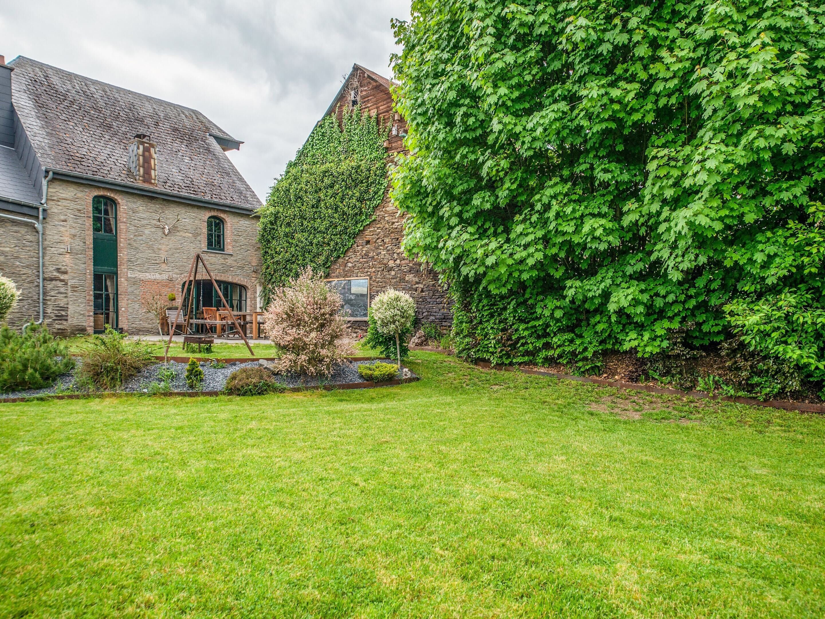 A stone building with a green door, a wooden swing set, and a well-maintained lawn.