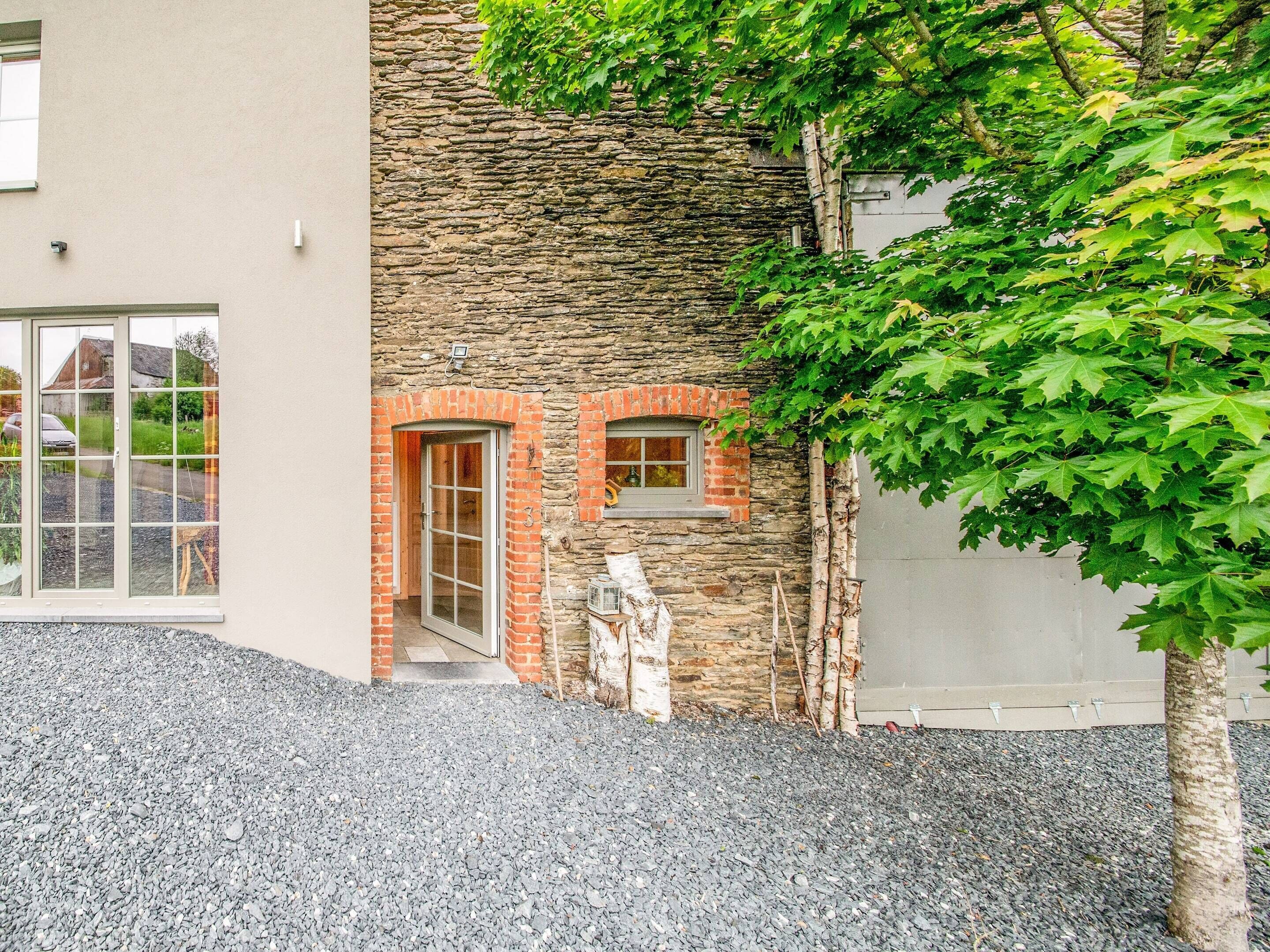 A modern building with a stone facade, a wooden door, and a small window.