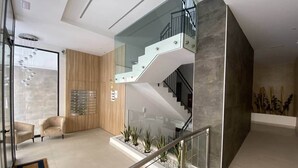 Ein modernes Interieur mit einer Glasstaircase, einer Wand aus Holzpaneelen und einer Sitzecke mit Sesseln.