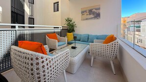 Ein Balkon mit Korbmöbeln, einer Couch und einem kleinen Tisch.