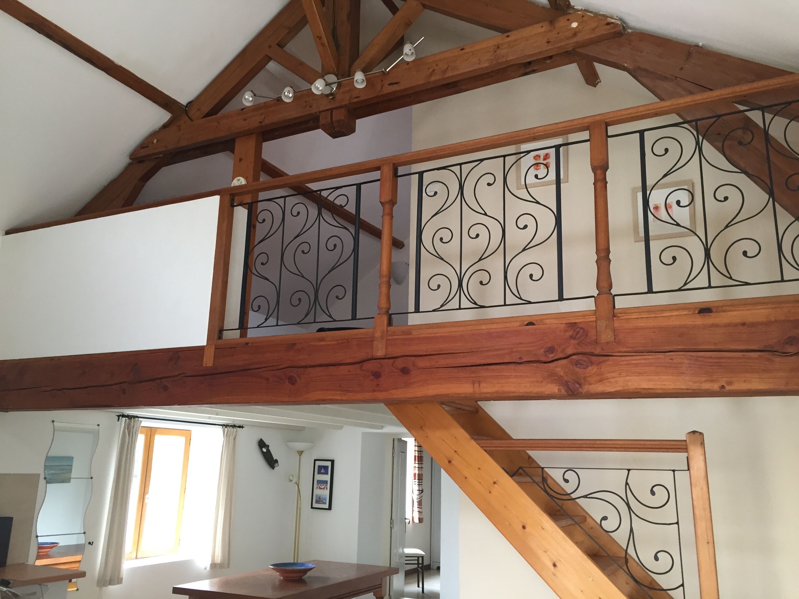 A wooden staircase with wrought iron railings leading to an upper floor.