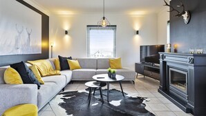 A modern living room with a grey sofa, a round coffee table, and a black and white cowhide rug. - Pleasant Holiday Home With Recreation Room (Bouillon)