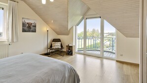 A bedroom with a large bed, a chair, a floor lamp, and a balcony with a view. - Pleasant Holiday Home With Recreation Room (Bouillon)