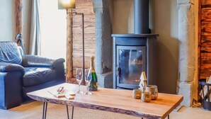 A cozy living room with a stone fireplace, a leather sofa, and a wooden coffee table. - Quietly Located Farmhouse L'echappee Belle (Manhay)