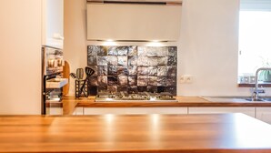 A modern kitchen with a central island, a built-in stove, and a stone backsplash. - Quietly Located Farmhouse L'echappee Belle (Manhay)