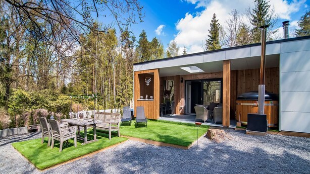 A modern house with a patio area, a wooden deck, and a fireplace. - Holiday Home in Biron With Barrel Sauna (Erezee)