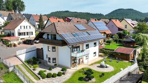 A residential house with solar panels, a balcony, and a well-maintained garden.