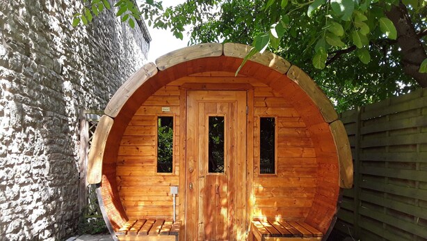 Une structure en bois dotée d’une porte, de deux fenêtres et d’un banc à l’extérieur.