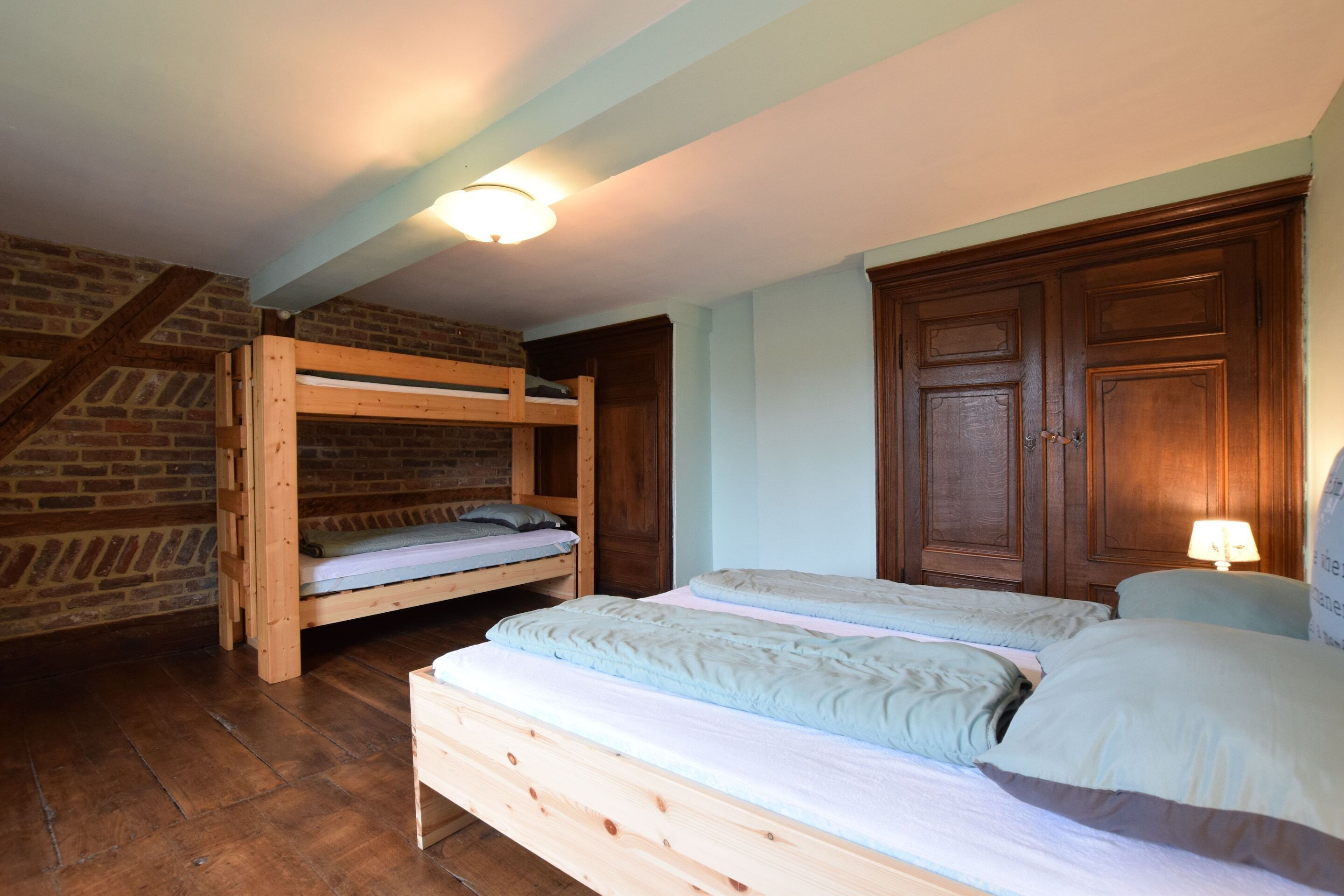 Een kamer met twee stapelbedden, houten kasten en een trap.