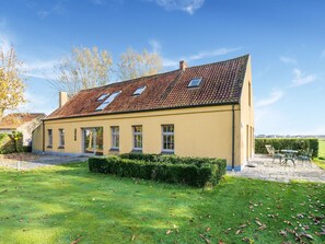 Ein zweigeschossiges Haus mit einem Ziegeldach, einer Veranda und einem gepflegten Rasen.