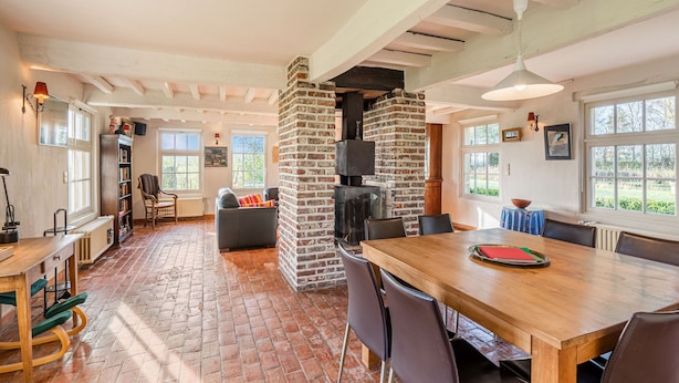 A spacious room with a brick fireplace, a dining table, and a cozy seating area. - Holiday Home Het Zuidgoed With Garden (Zedelgem)