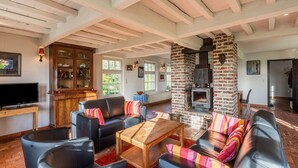 A living room with a fireplace, leather sofas, a wooden coffee table, and a television. - Holiday Home Het Zuidgoed With Garden (Zedelgem)