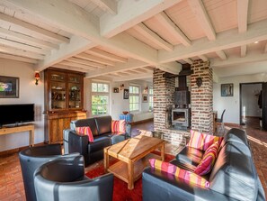 Ein Wohnzimmer mit Kamin, Ledersofas, einem Holztisch und einem Fernseher.