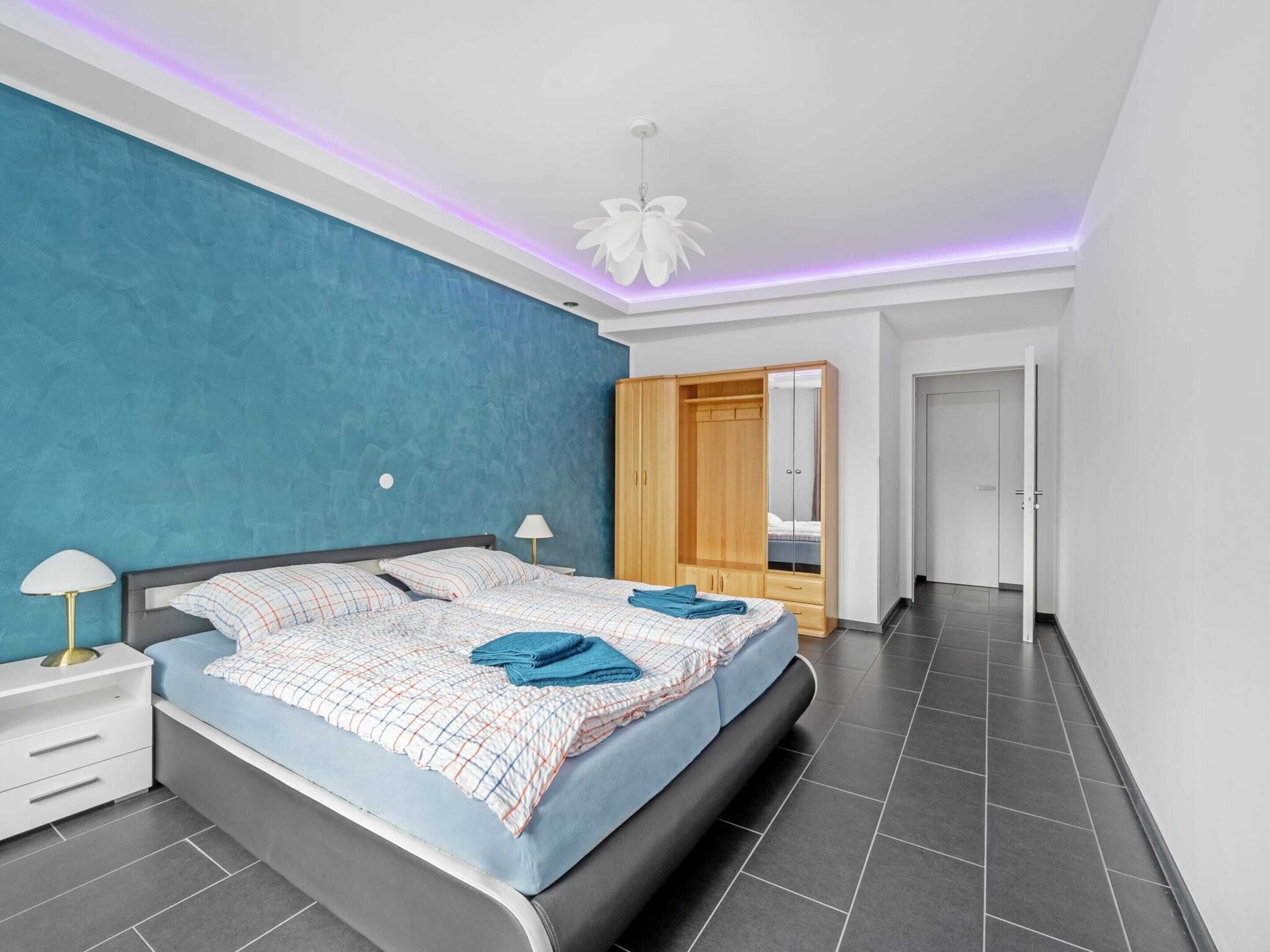 Une chambre moderne avec un grand lit, une armoire et un ventilateur de plafond.