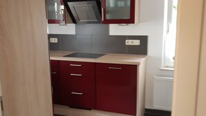 A kitchen with red cabinets, a stainless steel range hood, and a window with a view. - Great Holiday Home With Terrace Near Saxon (Hohnstein)