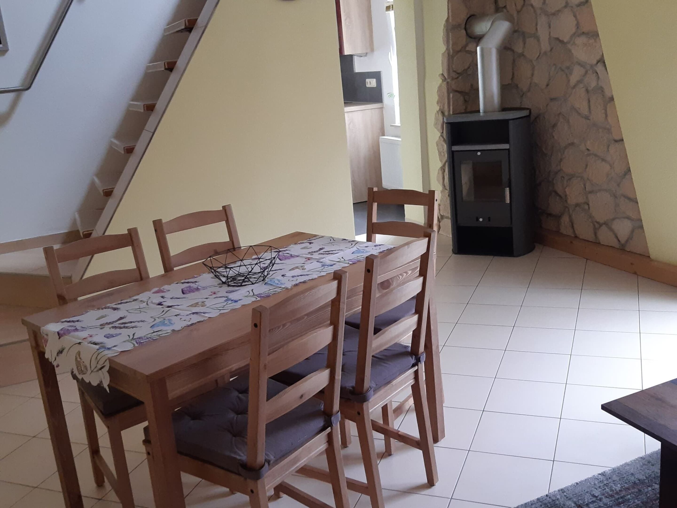 A dining area with a wooden table and chairs, a decorative bowl, and a stone wall with a fireplace.