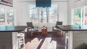 A room with a large window, two chairs, a small table, and a TV mounted on the wall. - Lake Murray Cottage w/ Private Dock, Fire Pit & Kayaks - Near Martin's Landing (Prosperity)