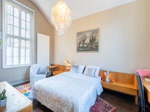 Une chambre à coucher avec un grand lit, un banc en bois, un bureau et une chaise.