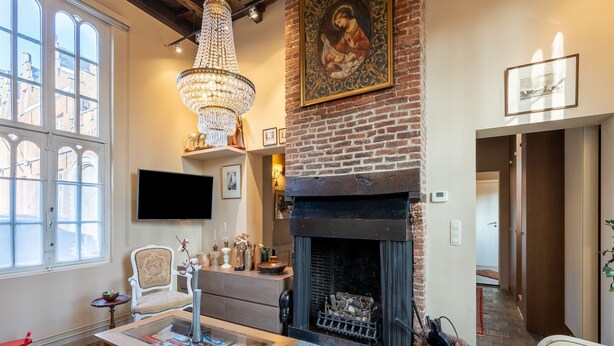 Un salón acogedor con chimenea, una araña y un gran ventanal.