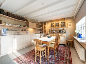 Una cocina moderna con armarios de madera, un comedor con mesa y sillas, y una alfombra estampada en el suelo.