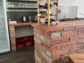 Et køkken med en mur-ø, reoler med vinflasker og røde kasser med flasker.