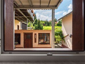 A window view of a building with a wooden door, a small window with flowers, and a metal railing. - Apartment in Saxon With Terrace (Sebnitz)