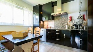 Uma cozinha moderna com armários escuros, bancada de granito e uma área de jantar com mesa e cadeiras.