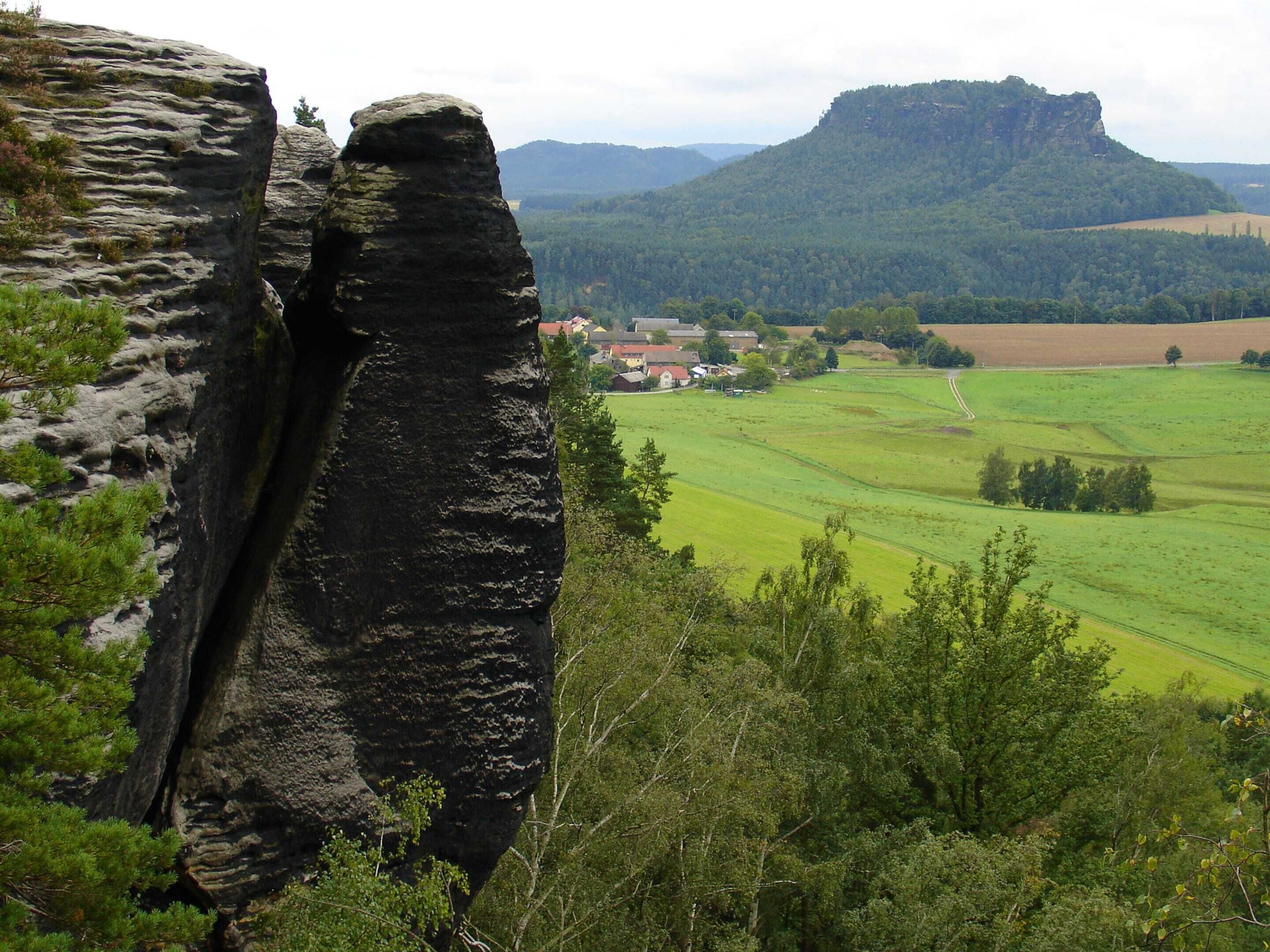 Eine natürliche Felsformation mit einem Dorf im Hintergrund.