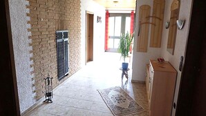 Un couloir avec un mur en briques, une grille métallique, un meuble en bois et une plante en pot.
