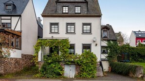 A two-story house with a gabled roof, multiple windows, and a small garden area with greenery. - Moselle Riverside Escape (Nehren)