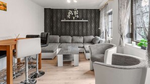 A modern living room with a sectional sofa, a dining table with bar stools, and a large window with curtains. - Moselle Riverside Escape (Nehren)