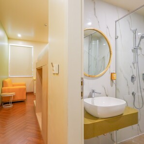 Un bagno moderno con un lavandino bianco, una doccia e uno specchio.