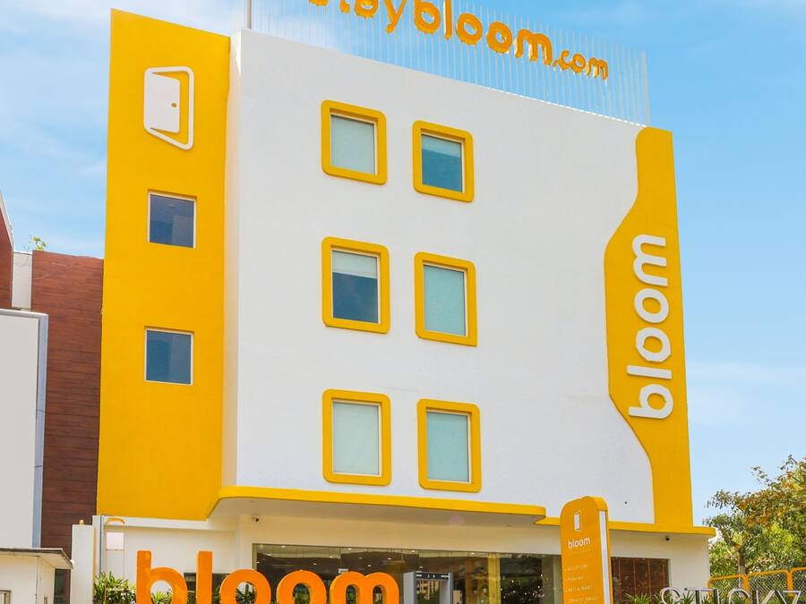 A building with a yellow and white facade, featuring the 'staybloom.com' logo at the top and 'bloom' on the side.